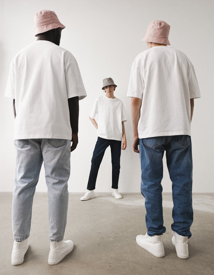 Three adults in bucket hats and denim in a minimalist setting.