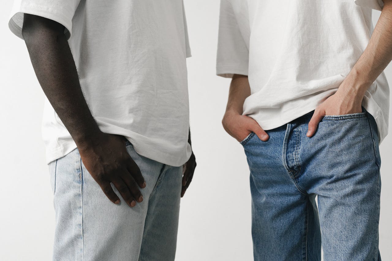 Close-up of two adults in white shirts and denim jeans, showcasing casual fashion style.